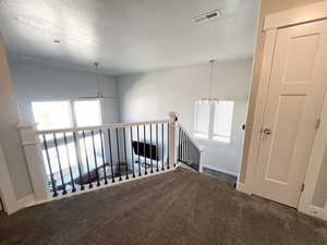 Corridor featuring dark carpet and a textured ceiling