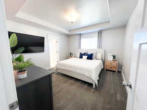 Carpeted bedroom featuring a tray ceiling and a textured ceiling