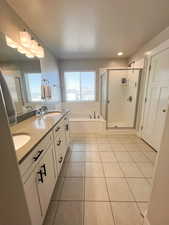 Bathroom with a textured ceiling, shower with separate bathtub, vanity, and tile patterned floors