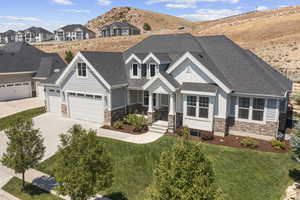 Craftsman inspired home with a mountain view, a garage, and a front lawn