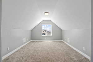 Bonus room with lofted ceiling, carpet flooring, and a textured ceiling