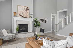 Living room with a fireplace, a towering ceiling, and light hardwood / wood-style floors