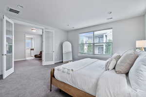 Carpeted bedroom with french doors, a textured ceiling, and ensuite bath