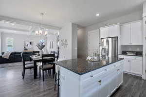 Kitchen with white cabinets, beam ceiling, a kitchen island, and stainless steel refrigerator with ice dispenser