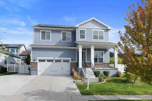 Craftsman inspired home with a garage, a front lawn, solar panels, and a porch