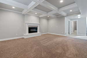 Unfurnished living room featuring beam ceiling, a high end fireplace, crown molding, and light colored carpet