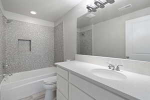 Full bathroom with tiled shower / bath, vanity, hardwood / wood-style floors, and toilet