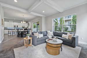 Living room featuring light hardwood / wood-style floors, a notable chandelier, ornamental molding, and beamed ceiling