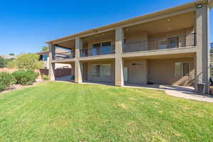 Back of house with a patio area, a balcony, and a lawn