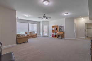 Carpeted living room with a wealth of natural light and ceiling fan