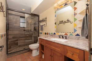 Bathroom featuring vanity, tile walls, a shower with shower door, and toilet