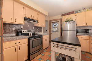 Kitchen featuring tasteful backsplash, appliances with stainless steel finishes, and cream cabinetry