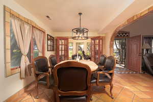 Tiled dining space featuring french doors and a notable chandelier