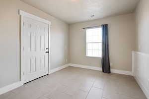 Empty room featuring a textured ceiling and light tile patterned floors