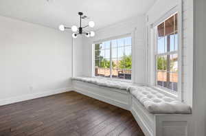 Unfurnished room with a notable chandelier and dark wood-type flooring