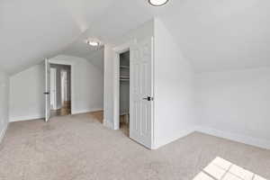 Additional living space featuring lofted ceiling and light colored carpet