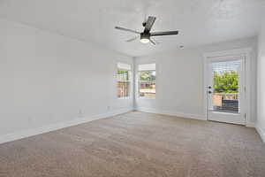 Unfurnished room featuring ceiling fan, light carpet, and a wealth of natural light