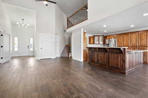 Kitchen featuring a breakfast bar, dark wood-type flooring, a towering ceiling, a large island, and stainless steel refrigerator with ice dispenser