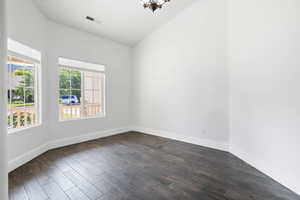 Empty room with lofted ceiling and dark hardwood / wood-style flooring