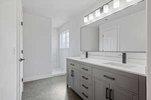 Bathroom with a tile shower, tile patterned floors, and vanity