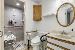 Bathroom with tile patterned flooring, tiled shower, vanity, and toilet