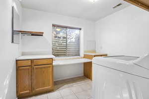 Clothes washing area featuring light tile patterned flooring