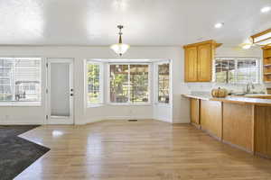 Kitchen with light hardwood / wood-style flooring, a wealth of natural light, and hanging light fixtures