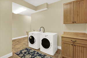 Washroom featuring cabinets and washer and clothes dryer