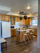 Kitchen with white appliances, a breakfast bar area, dark wood-type flooring, sink, and a center island