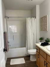 Full bathroom with shower / tub combo, hardwood / wood-style floors, vanity, and toilet