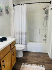 Full bathroom with shower / tub combo with curtain, hardwood / wood-style floors, vanity, and toilet