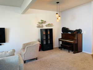 Living area featuring light colored carpet and beam ceiling