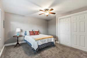 Carpeted bedroom featuring a closet and ceiling fan