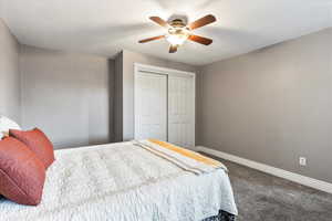 Carpeted bedroom featuring ceiling fan and a closet