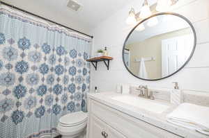 Bathroom with vanity, a textured ceiling, toilet, and curtained shower