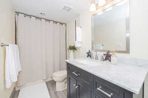 En Suite Bathroom with vanity, walk-in shower, wood-type flooring, a textured ceiling, and toilet