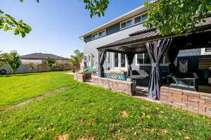 Back of house featuring a yard, a gazebo covering stamped concrete patio