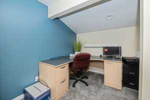 Carpeted home office nook featuring a textured ceiling and lofted ceiling with beams