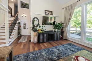 Foyer entrance featuring lofted ceiling, a chandelier, and hardwood flooring