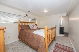 Bedroom with a textured ceiling and light colored carpet