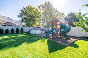 View of playground and heated above ground pool, with a yard and a mountain view