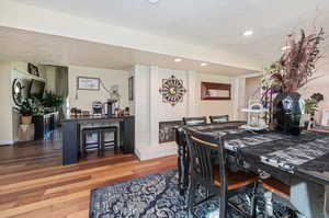 Dining space featuring a textured ceiling, hardwood flooring, and a fireplace