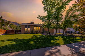 Twighlight View of front of property featuring a lawn