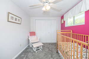 Bedroom featuring ceiling fan, a textured ceiling, carpet, a nursery area, and a closet