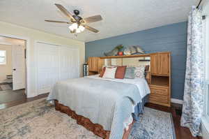 Bedroom featuring a closet, a textured ceiling, connected bathroom, dark hardwood / wood-style flooring, and ceiling fan