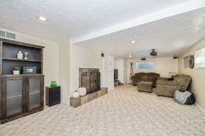 Living room featuring carpet and a textured ceiling, with a fireplace