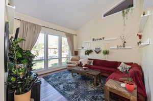 Living room featuring hardwood flooring and vaulted ceiling, picturesque windows