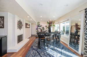 Dining area featuring a textured ceiling, hardwood  flooring, and a fireplace