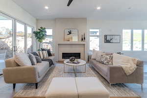 Living room featuring ceiling fan, a fireplace, and a healthy amount of sunlight