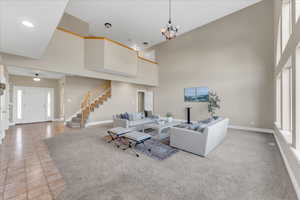 Living room with a high ceiling, light carpet, and a notable chandelier